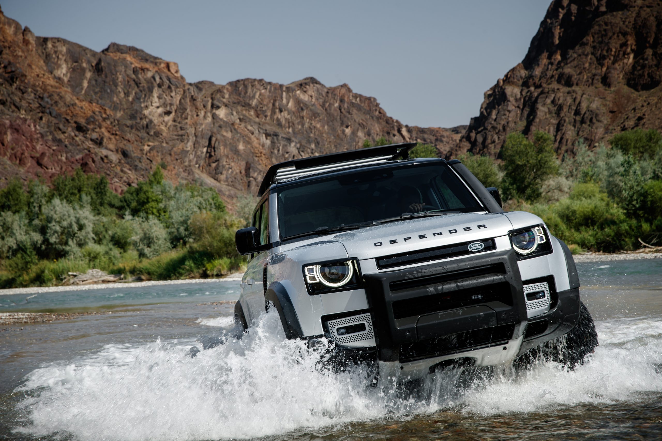 New Land Rover Defender front three-quarter off-road river crossing action